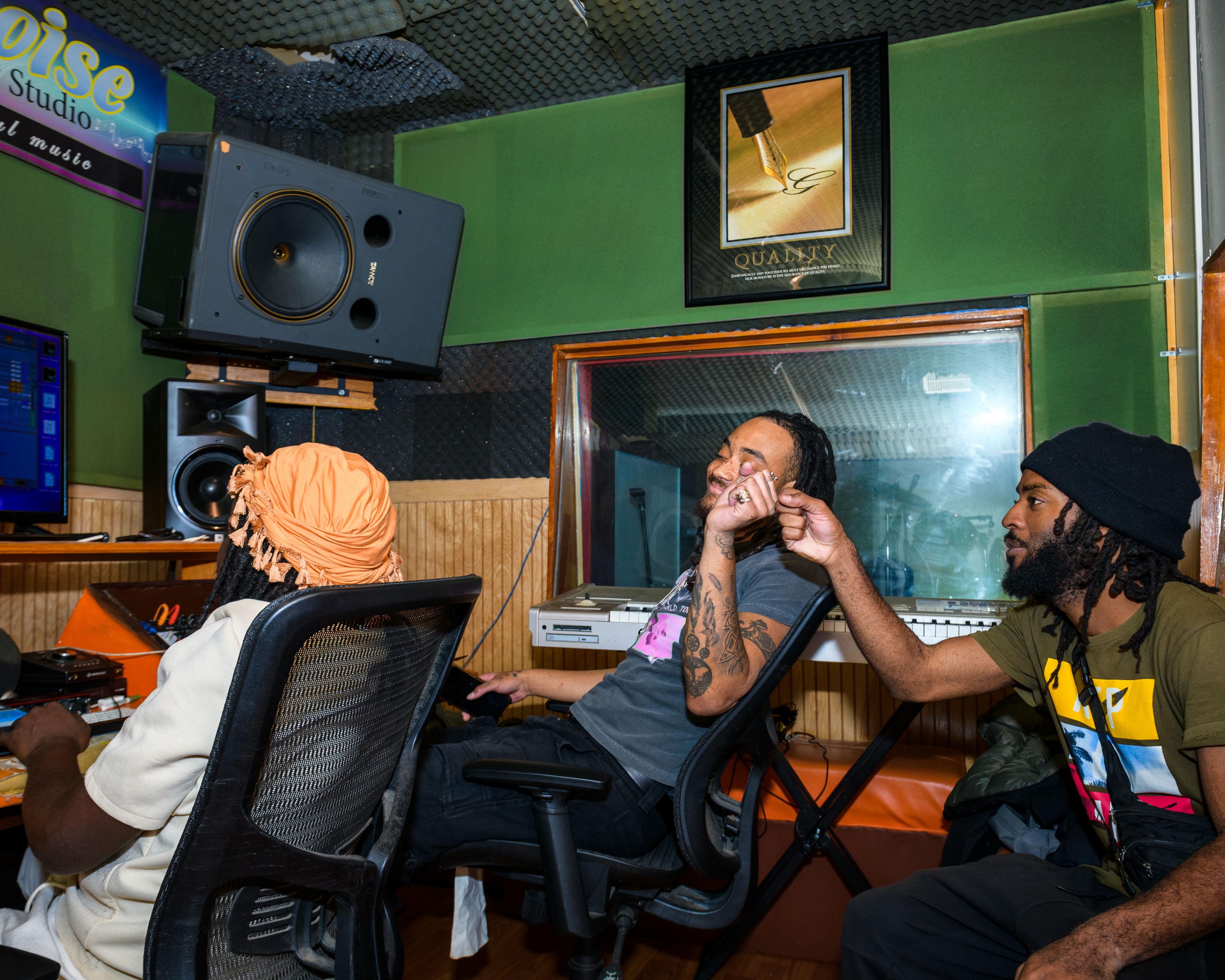 Rehearsal room session with artists gathered at the desk and playback position.